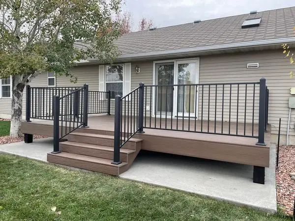 Composite backyard deck with black metal railings and custom steps built by Bald Ridge Enterprises in Cody, Wyoming.