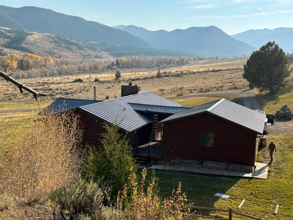 Cabin cluster with new metal roofing set against a scenic mountain valley backdrop.