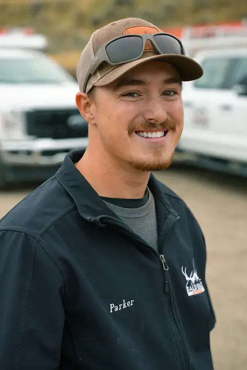 Bald Ridge employee wearing a black hoodie standing outdoors with company trucks in the background.